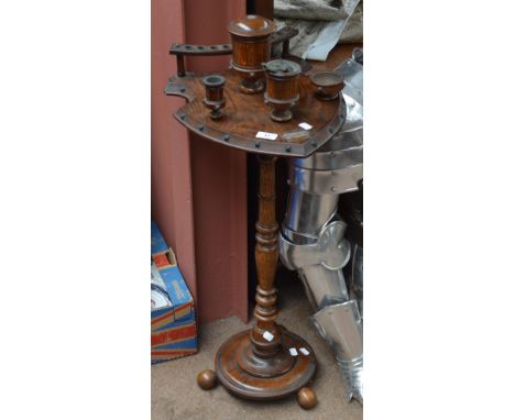 An early 20th century oak smoker's stand with shield shaped platform set with four trinket pots and an aperture for pipes, he