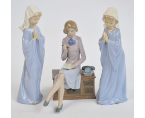 Three Nao figures; lady seated on a telephone table and two young girls as nuns. CONDITION REPORT: Appears good with no obvio