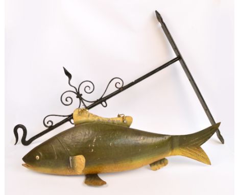 An unusual painted tin fish hanging sign, suspended on a wrought iron wall mounted scrolling bracket, length of fish 100cm. C