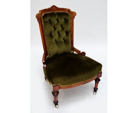 A late Victorian walnut and amboyna inlaid button upholstered nursing chair raised on ring turned front legs.