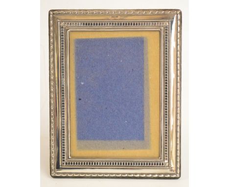 A modern hallmarked silver rectangular photograph frame with velvet easel back with dentil and oval banded pattern, Walker & 