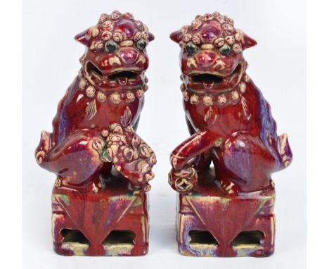 A pair of late 19th century Chinese porcelain Kangxi style Buddhist lions, male and female, with a rich flambé glaze, on pier