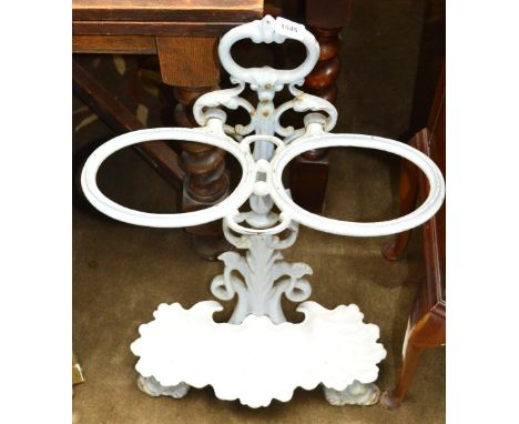 A cast iron stick stand with twin oval upper apertures above stylised dolphin supports and shell moulded drip tray.