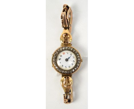 A vintage lady's 9ct gold wristwatch with diamond set bezel, white enamel dial with Arabic numerals and expanding strap (af).