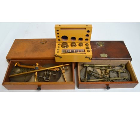 Two early 20th century mahogany and oak cased brass jewellery scales, width of cases 30cm and 26cm, also a cased set of brass