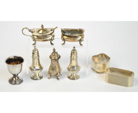 A George V hallmarked silver three piece cruet set with shaped rim, raised on four outswept feet, comprising baluster pepper,