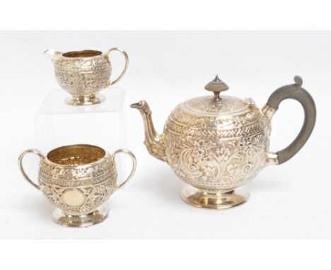 A Victorian hallmarked silver three piece Indian style tea service, comprising a globular teapot embossed with floral and fol