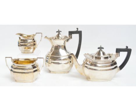 A George V hallmarked silver four piece tea service comprising a teapot of shaped rectangular form with cast decorated rim an