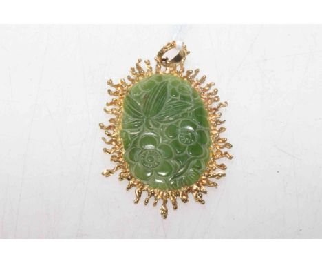 A Chinese carved jade pendant, the oval jade plaque carved with flowerheads and leaves, the mount with irregular edge, the ba
