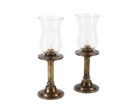A PAIR OF BRASS STORM LANTERN CANDLESTICKS  EARLY 20TH CENTURY  Each with tulip-shaped shade above the stem and spread foot, 