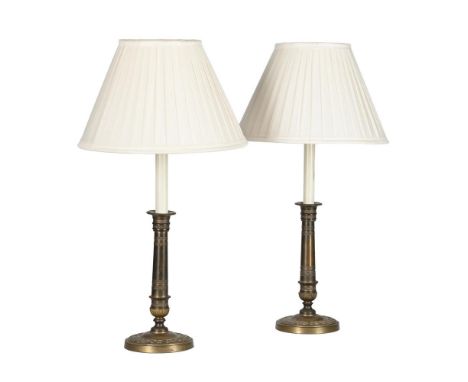 A PAIR OF BRASS TABLE LAMPS IN EMPIRE STYLE, 20TH CENTURY  With pleated shades above a simulated candle-fitment, the lamp bas