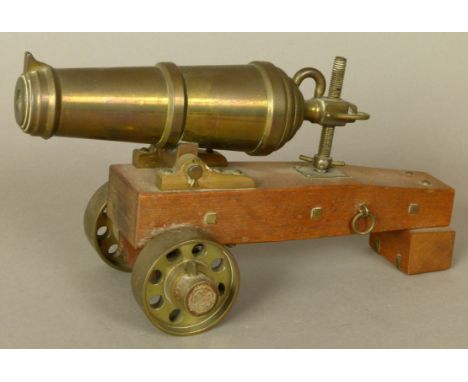 A REPRODUCTION BRASS MINIATURE CARRONADE CANNON with naval carriage and brass wheels, 21cm long overall 