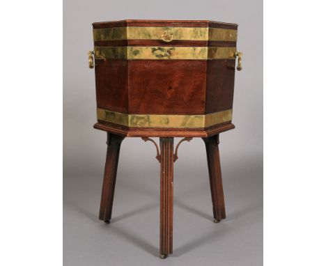 A GEORGE III BRASS BOUND HEXAGONAL MAHOGANY CELLARETTE, the hinged lid with axe head handles revealing lead lined fitted inte