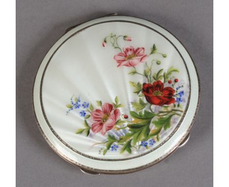 A SILVER AND ENAMELLED POWDER COMPACT of circular outline, the cover painted with poppies, peonies and forget-me-nots against