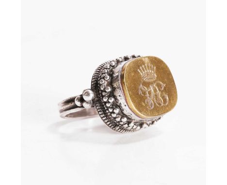 An Anglo-Indian silver and gilt-metal ring, the gilt-metal oval panel possibly initialled 'M G C', with a crown above, the se