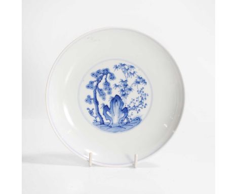 A Chinese blue and white dish, Kangxi (1662-1722), of circular form, painted with bamboo, prunus and pine by a rock, the unde