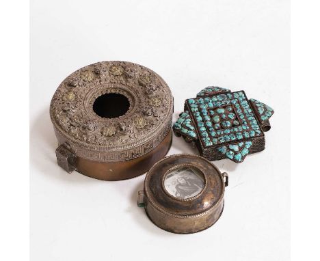 A white-metal and copper amulet box, 19th century, the cover with gilt-metal Buddhist emblems, within a white-metal all-over 