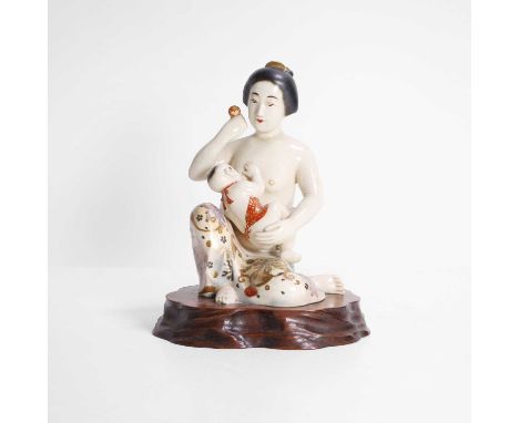 A Japanese Kutani ware okimono, Meiji period (1868-1912), of a maiden breastfeeding a baby, her lower garment decorated with 