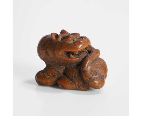 A Japanese wood netsuke, Meiji period (1868-1912), of a recumbent tiger, signed to base,4cm longProvenance: Purchased by the 
