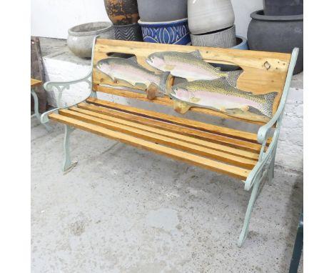 A teak slatted garden bench with cast iron ends, painted with fish decoration by Clive Fredriksson. 124x74x60cm. 