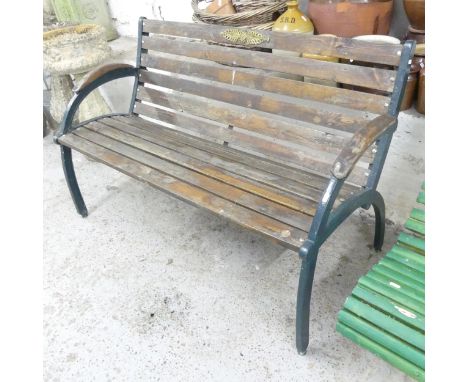 A teak slatted garden bench with cast iron ends. 132x82x62cm. 