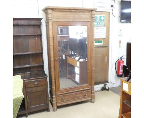 An antique pitch pine and bamboo effect armoire, with single mirrored drawer, shelf fitted interior and single drawer to base