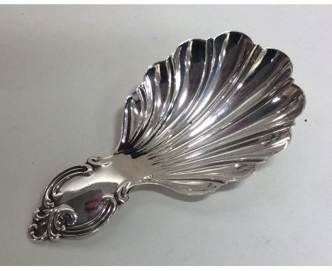 A Victorian fluted silver caddy spoon with scroll thumb piece. Sheffield. Approx. 12 grams. Est. £30 - £40.
