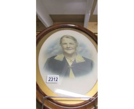 An oval framed and glazed portrait of an elderly lady.