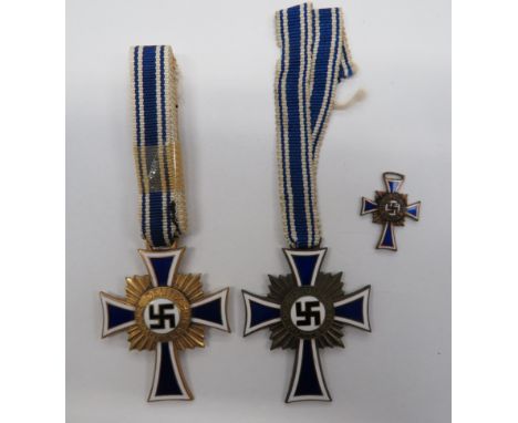 German Third Reich. 1st and 3rd Class Mothers Crosses and a miniatureA gilt example and a bronzed example in blue and white e