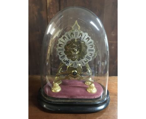 A brass skeleton clock under a glass dome.