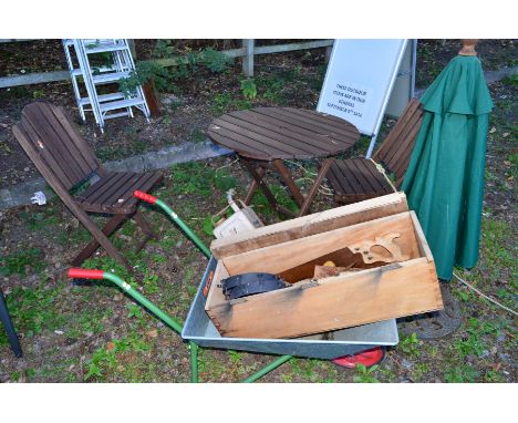 A SMALL CIRCULAR TEAK GARDEN TABLE, diameter 76cm, two matching folding chairs, together with a metal wheel barrow, parasol, 