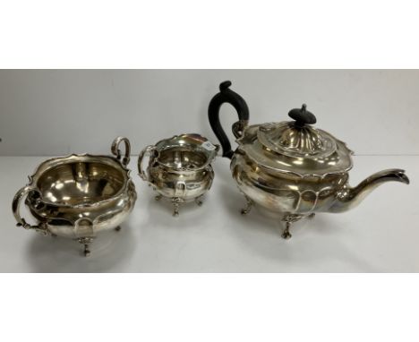 An Edwardian silver three piece tea set of squash form raised on four scroll feet comprising tea pot with ebonised handle and