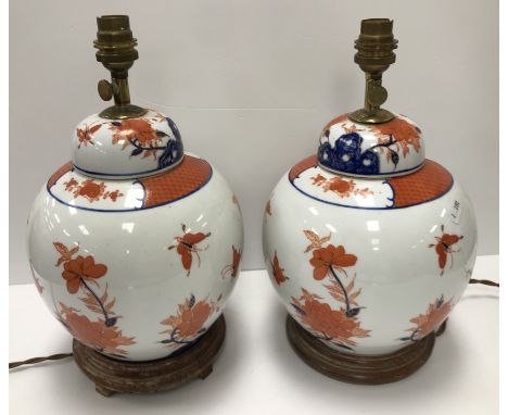 A pair of Japanese porcelain butterfly and flower decorated table lamps of ginger jar form in the Kutani manner raised on tur