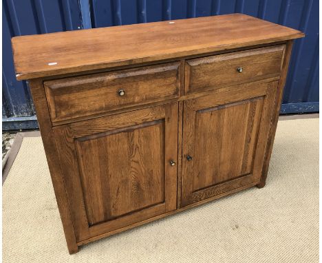 A 20th Century oak side cabinet, the plain top over two drawers and two fielded panelled doors on stile supports, 112 cm wide