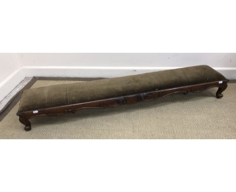 A Victorian mahogany kneeler stool with drop-in upholstered seat within a scrolling foliate decorated frieze on cabriole legs