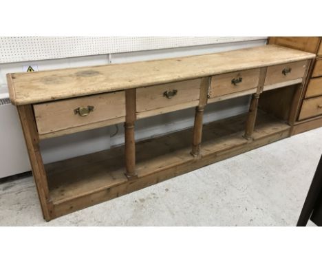 A Victorian pine dresser, the single piece plank top over four drawers on pitch pine turned column supports united by a pot s