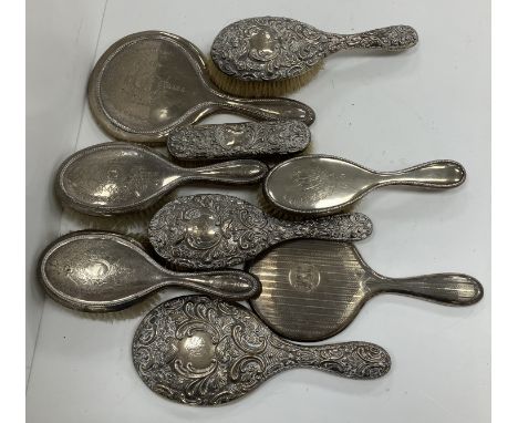 A silver backed three piece dressing set with two hairbrushes and mirror with beaded decoration, another embossed silver dres