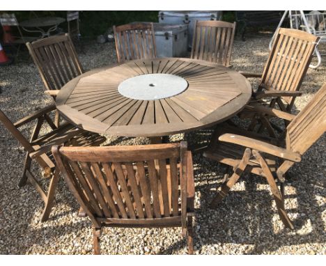 A round teak garden table with Lazy Susan centre, 160 cm diameter x 75 cm high, together with seven wooden folding chairs and