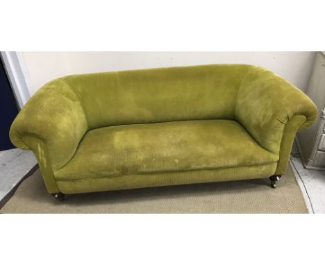 A Victorian Chesterfield sofa in modern lime green corduroy upholstery raised on ringed and turned front legs to brass caps a