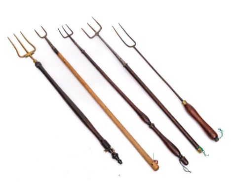 A brass three pronged toasting fork: with turned and ebonised handle, two metal three pronged forks with turned wood handles 