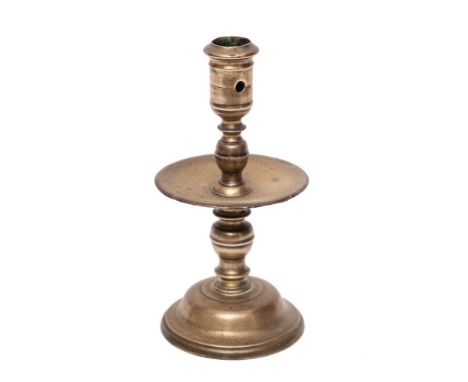 A mid 17th Century Dutch cast brass 'Heemskirk' candlestick: with turned stem, wide central drip pan and mound base, 20.5cm h