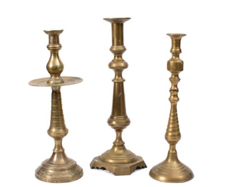 A brass candlestick: in the 17th Century taste, the baluster and ribbed stem with wide drip pan and circular base, 42cm high,
