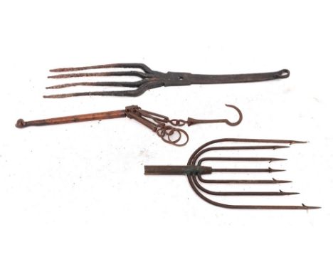 An iron eel fork: with seven tines, an iron four pronged fork and an iron pot carrier with twin rings and wood handle. (3)