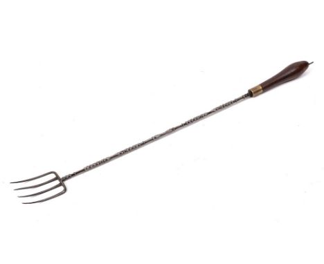 A metal four pronged toasting fork:, the handle with shaped shaft and turned wood baluster terminal, 18th/early 19th Century.