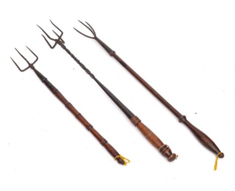 An iron four pronged flesh fork: with turned wood handle and two iron three pronged flesh forks with turned wood handles. (3)