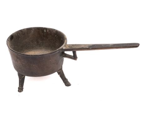 A 17th/18th Century brass skillet: of circular form, the handle with open bracket, on tripod splayed legs (South East Region)