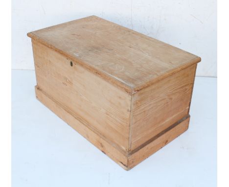 A waxed pine trunk or blanket box - the moulded top on iron strap-hinges, enclosing an interior with till, on a bevelled plin