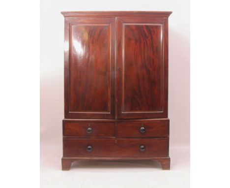 An early to mid-19th century mahogany linen press - the moulded cornice over a pair of chamfered panelled doors enclosing fou