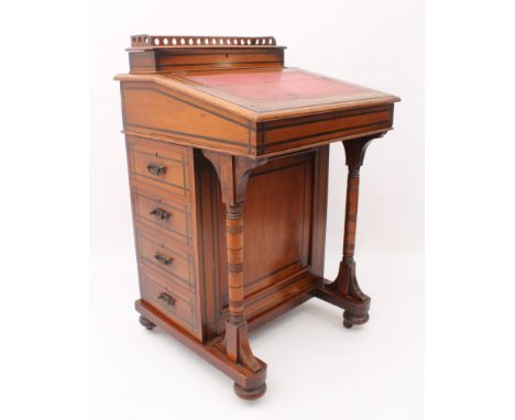 A late-Victorian ebony inlaid walnut Davenport in the Aesthetic taste - the pierced gallery top opening to reveal a fitted st