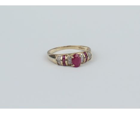 A 9ct yellow gold, ruby and diamond ring - Sheffield hallmarks, the central oval cut ruby flanked by three rows of single cut